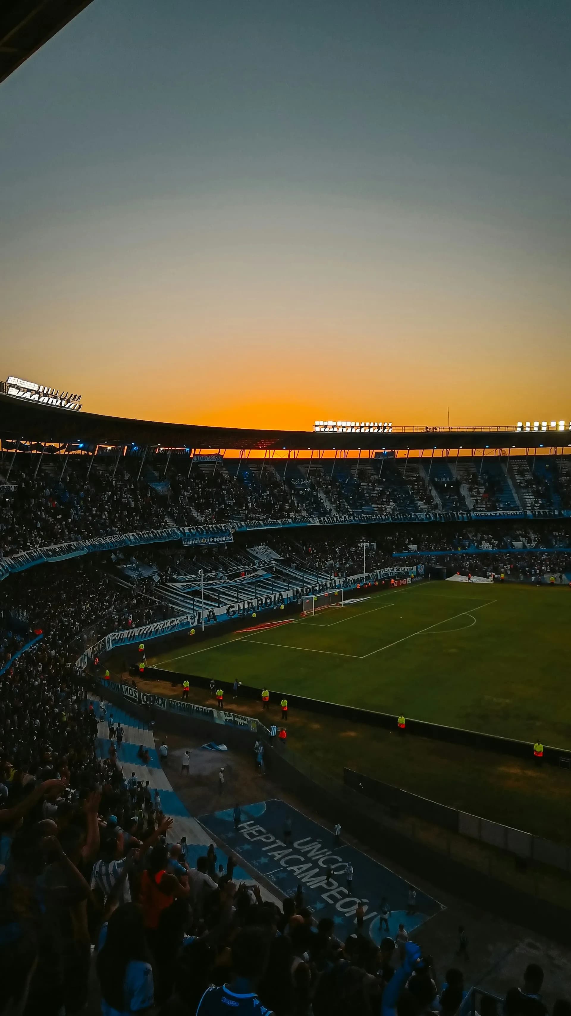A packed stadium as the sun sets behind the stand